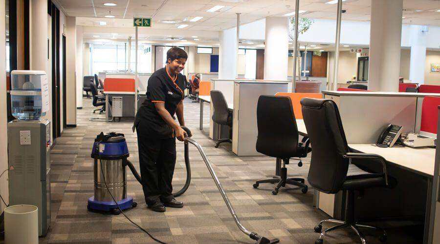A 3Z's Cleaning team member vacuuming an open-plan office